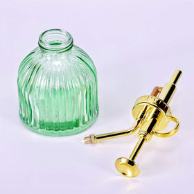 Aebor green glass spray bottle adds decorative appeal near plants.