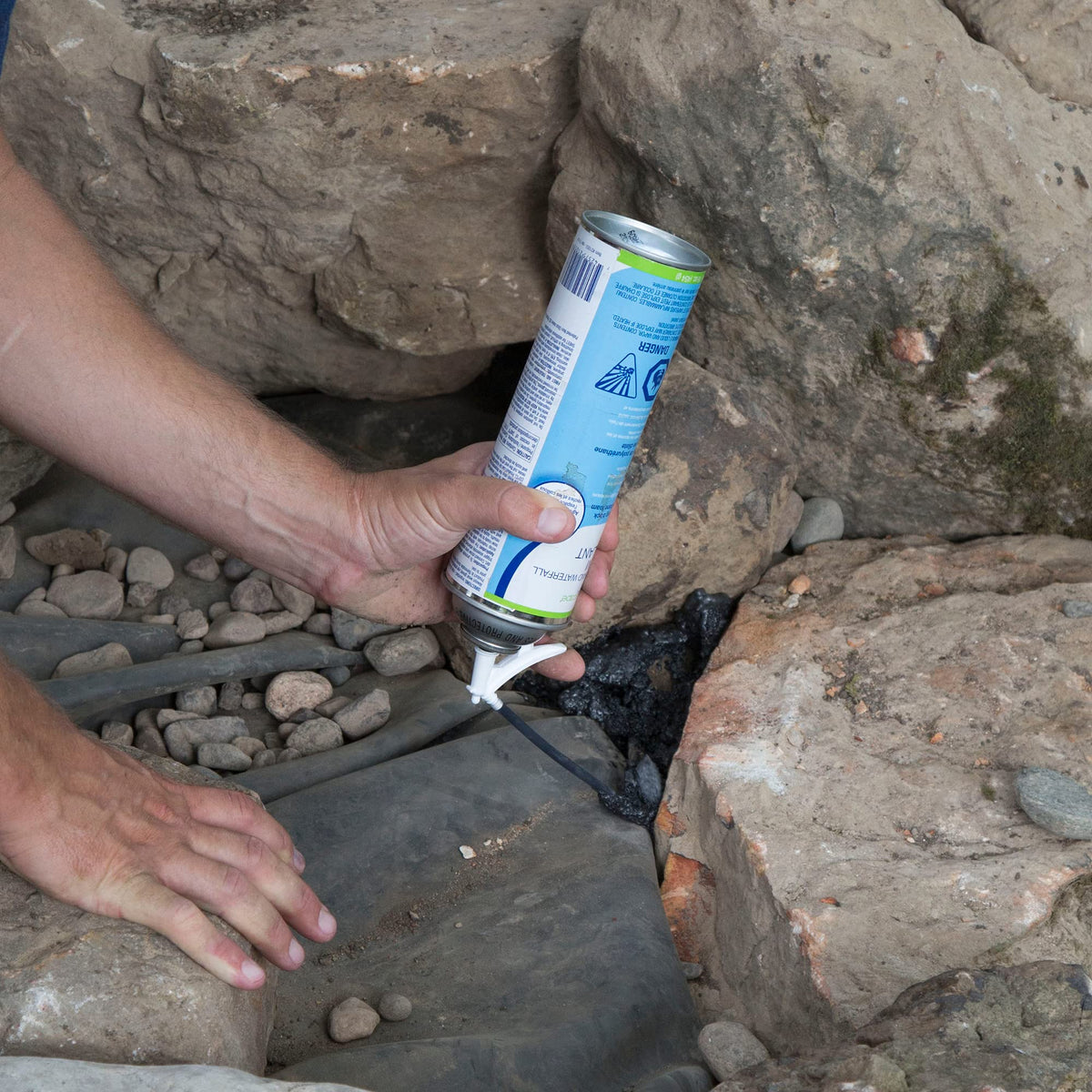 Aquascape foam sealant between stones directs water paths in a pond feature.