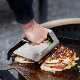Breeo Griddle Press on a flat-top grill demonstrates universal compatibility.