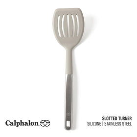 Calphalon Prime slotted turner with stainless steel handle offering sturdy control during cooking.