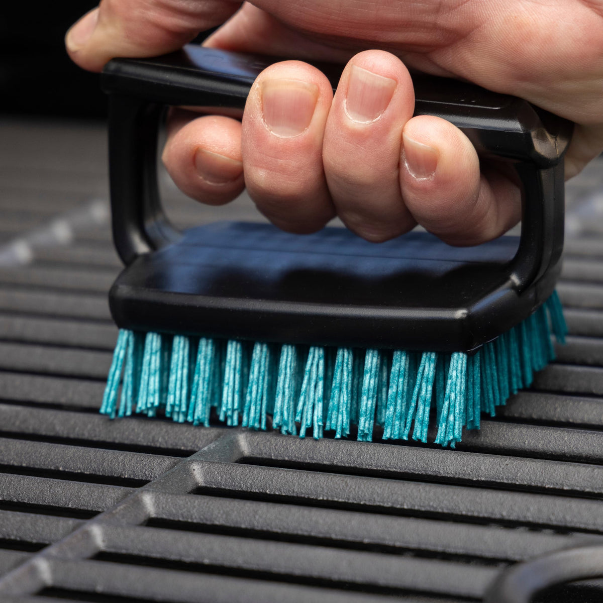 Charbroil Safer Handheld Grill Brush cleaning grates image demonstrates grit-infused bristles for thorough cleaning.