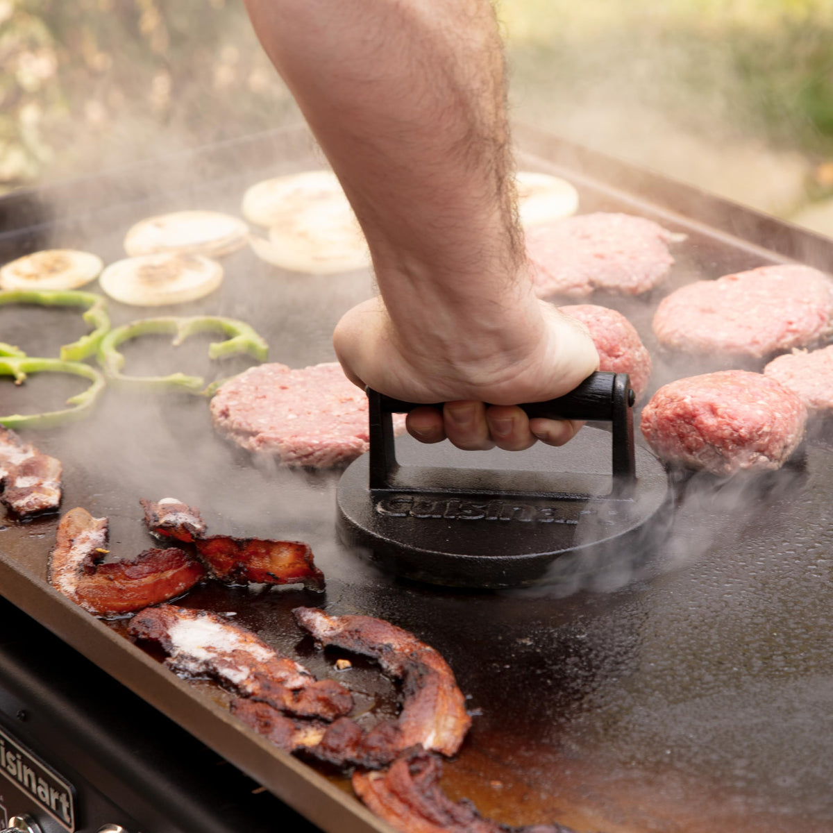Cuisinart cast iron press in an outdoor cooking setup for versatile grilling.