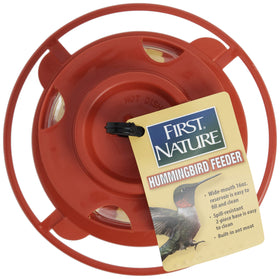 First Nature hummingbird feeder hanging from a hook or limb in outdoor setting.