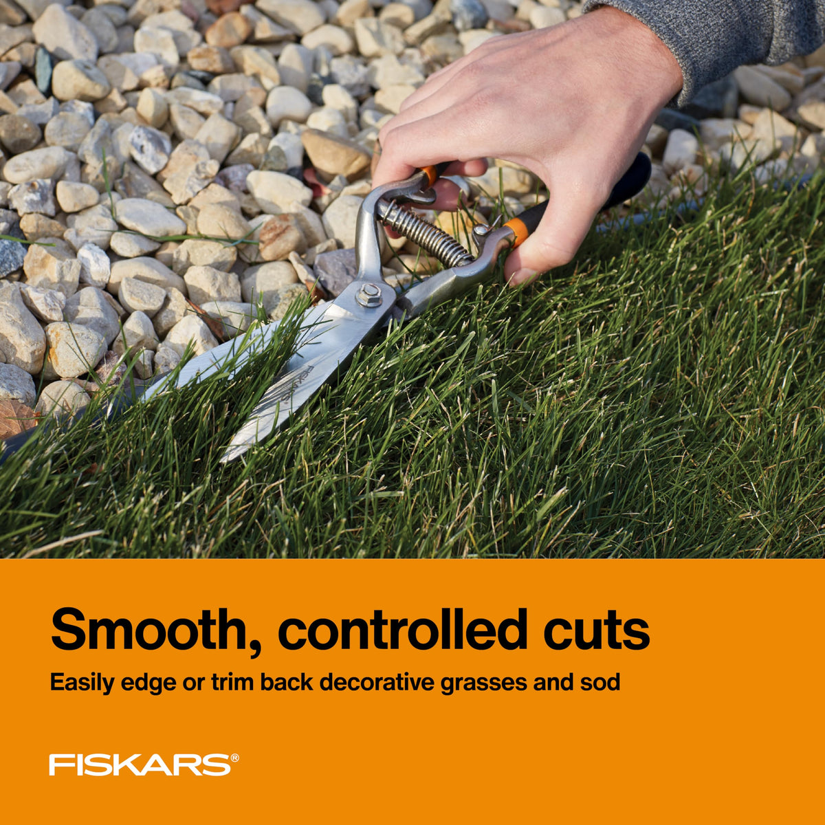 Fiskars grass shears in hand show ergonomic non-slip grip for trimming.