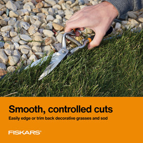 Fiskars grass shears in hand show ergonomic non-slip grip for trimming.