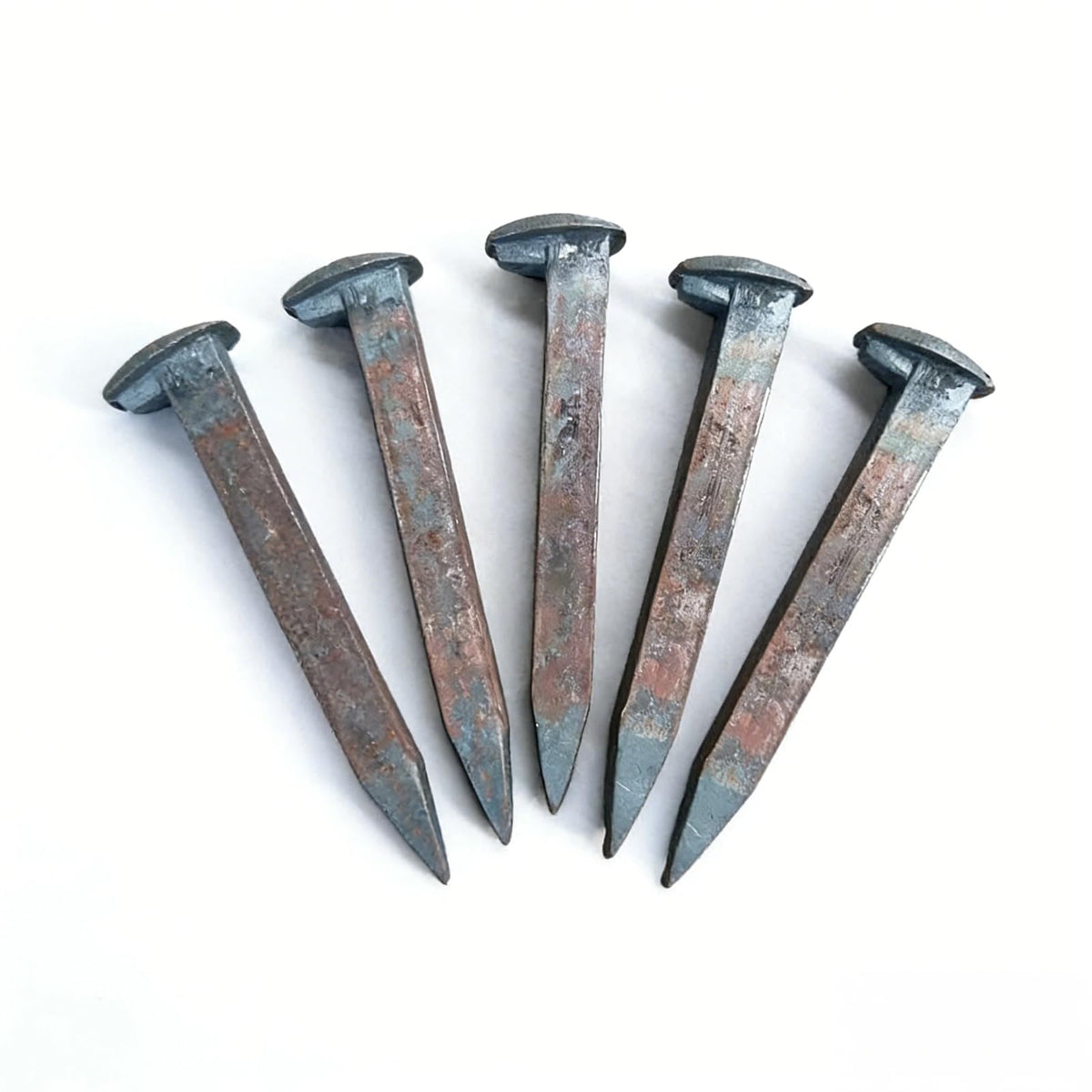 Generic railroad spikes arranged in a row for forging and DIY projects.
