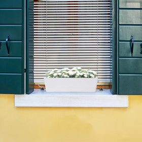 Outdoor balcony scene featuring GREANER planter with drainage holes.