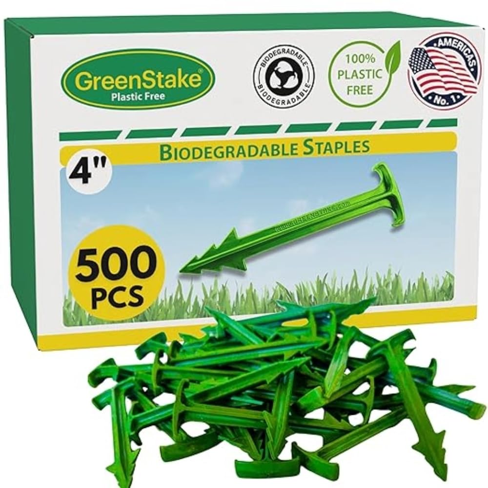 GreenStake 4-inch biodegradable stakes securing landscape fabric in soil.