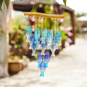 Glassy blue fish wind chime catches sun, perfect for beach weddings and patios.