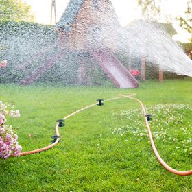 Hourleey garden hose guide assembly shown in yard setting.