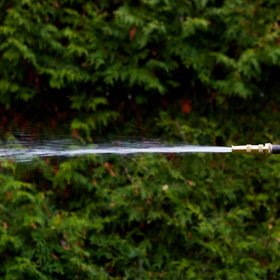 Hourleey hose nozzle in use for watering garden and cleaning car.