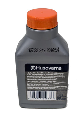 Husqvarna XP 2-cycle oil bottle in hand for maintenance.