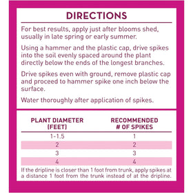Spikes installed in soil beside an azalea shrub for targeted feeding.