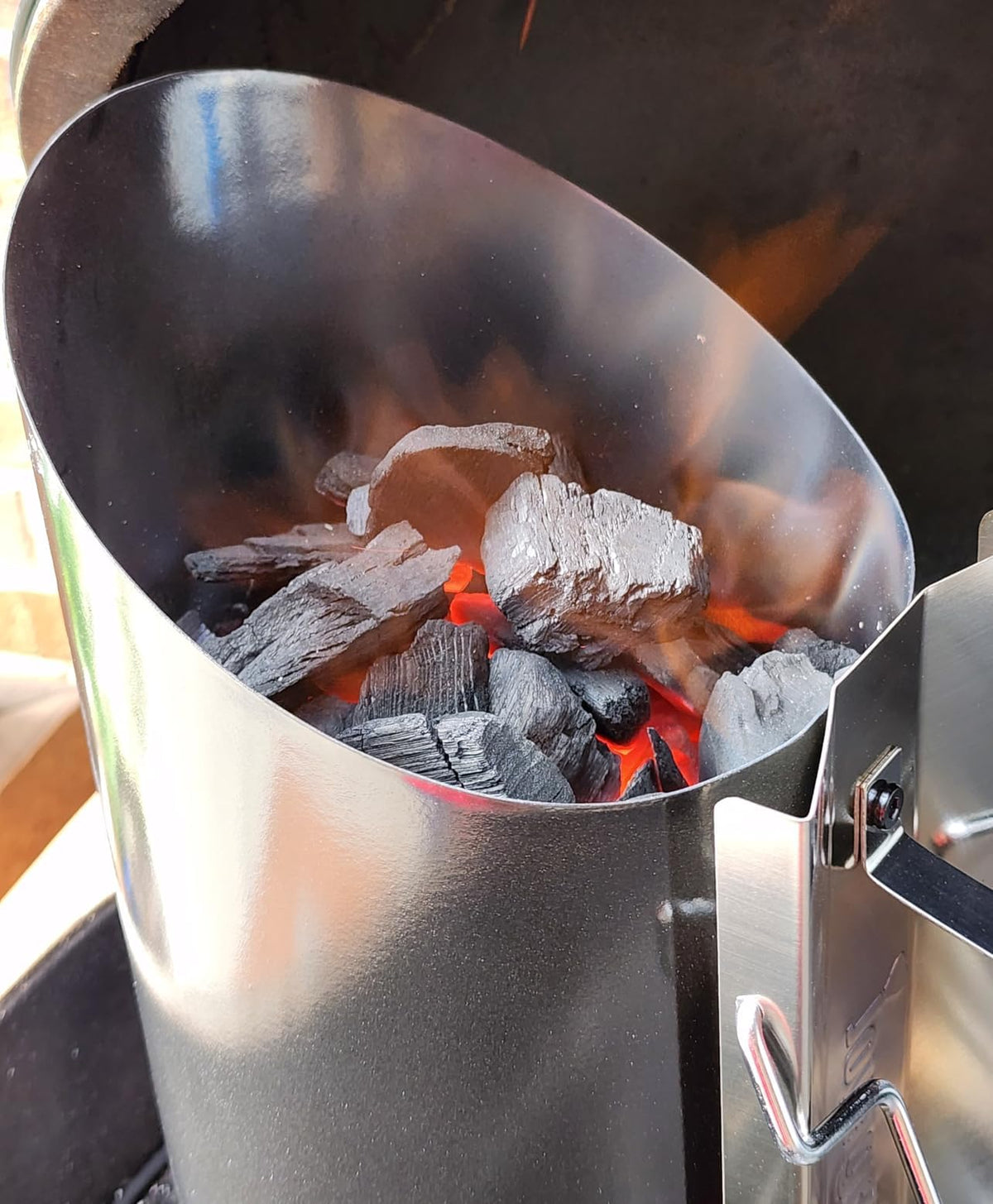 Joyagrill charcoal being dumped through shovel outlet for controlled burn.