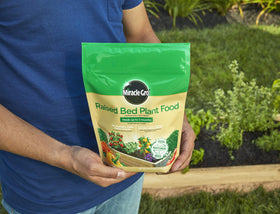 Measuring Miracle-Gro Raised Bed Plant Food into soil before planting.