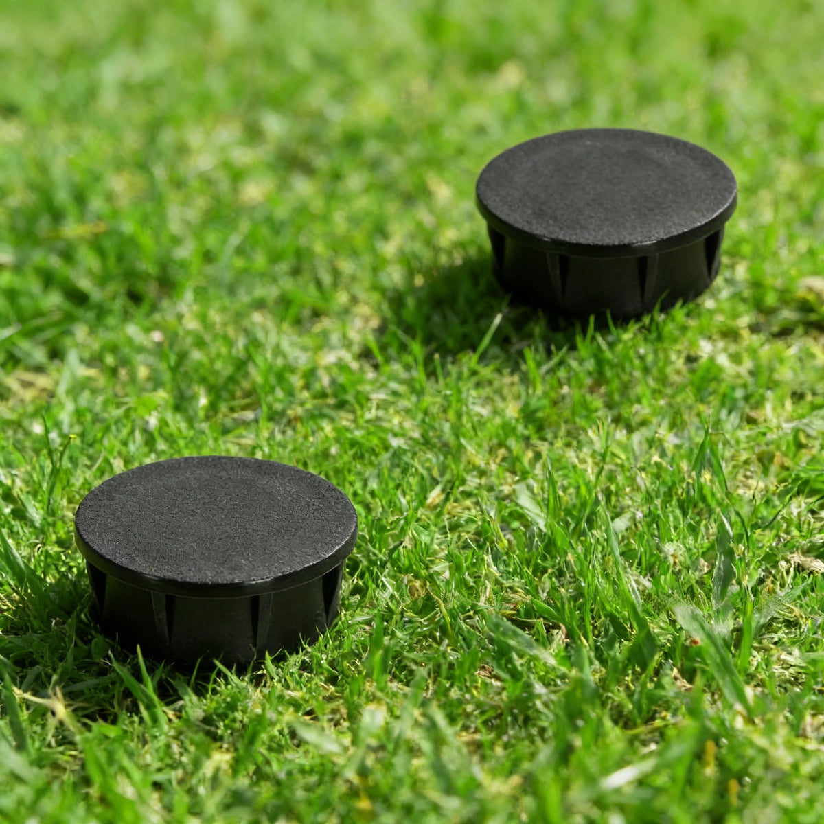 Mizelu black sprinkler head cap outdoors, emphasizing discreet, weather-ready cover.