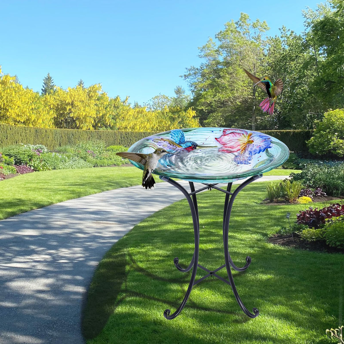 Glass bird bath on a metal stand showcased in a sunny garden