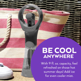 O2COOL Elite misting fan grey in use outdoors at beach or park for relief.