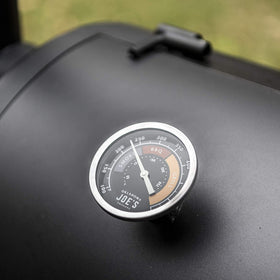 Oklahoma Joe's glow dial gauge next to grill tools for quick reference