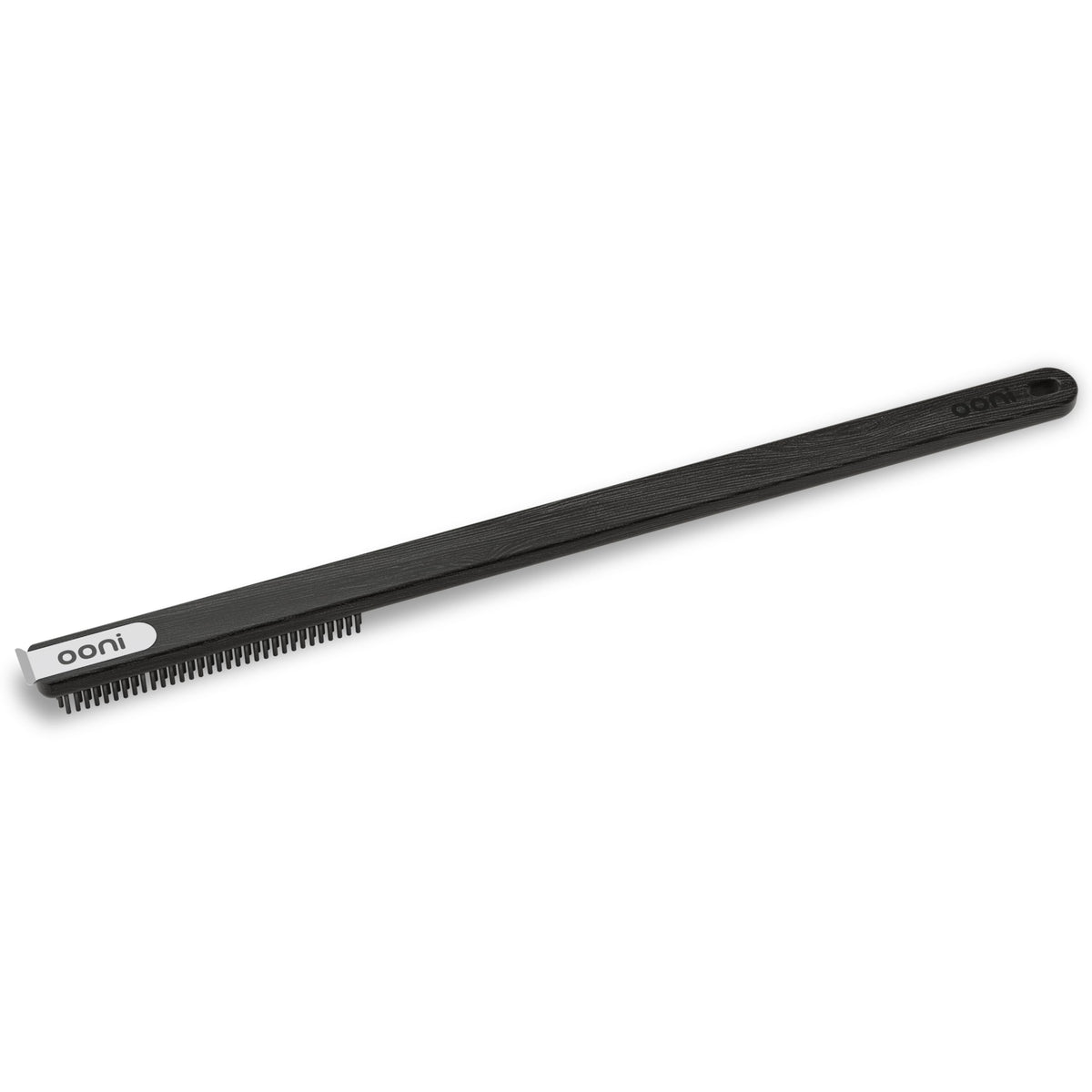 Ooni wire brush-scraper bristles close-up cleaning ash from a stone.