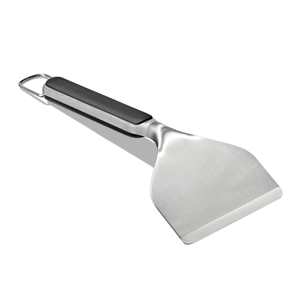OXO Outdoor Griddle Scraper angled head cleaning residue safely on hot surfaces.