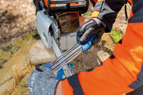 PFERD chainsaw bar filing vise drives into a tree stump for secure anchoring.
