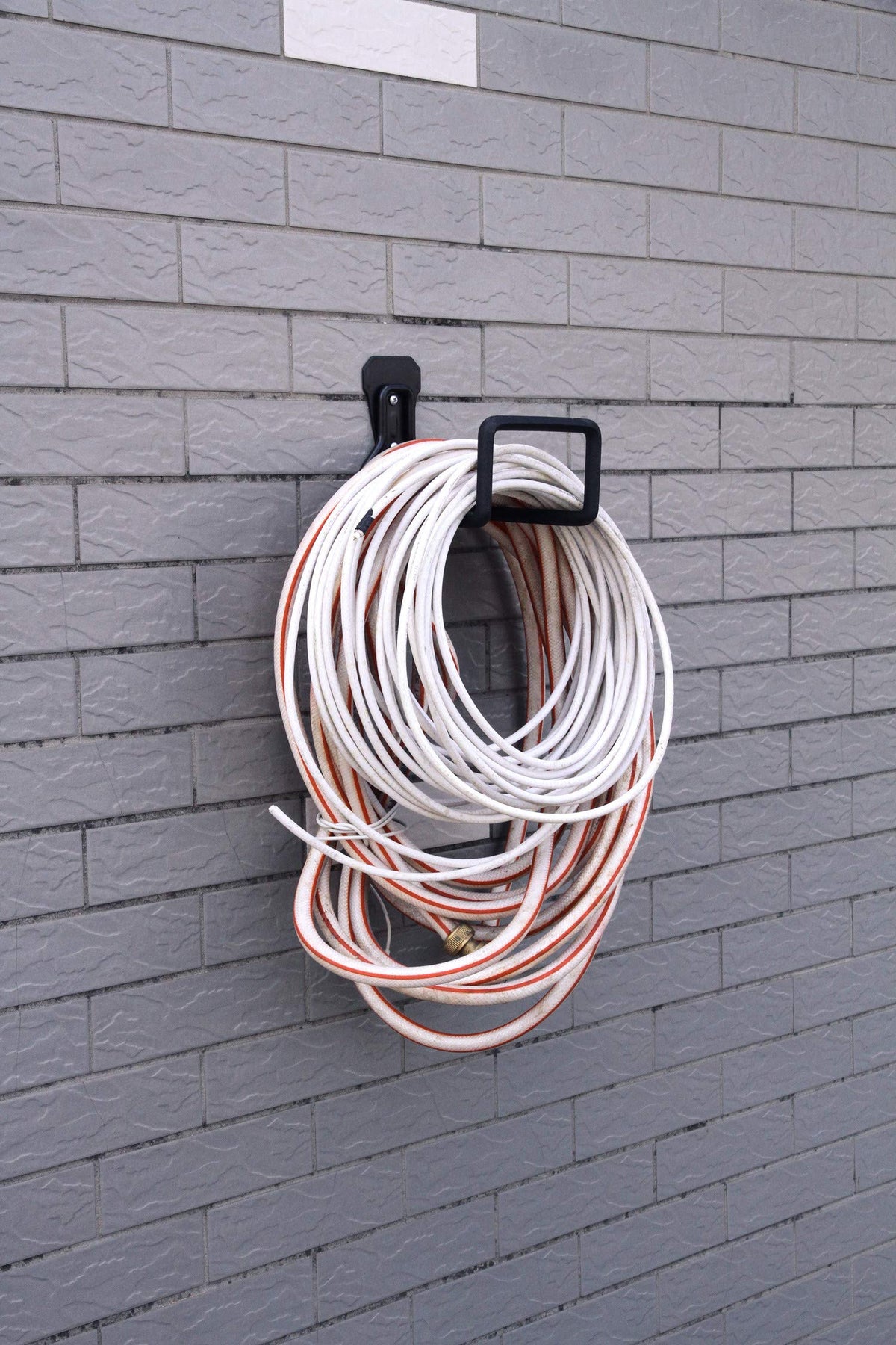 Sageme hose holder installed on wall keeps hoses protected from twist and kink.