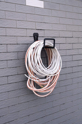 Sageme hose holder installed on wall keeps hoses protected from twist and kink.