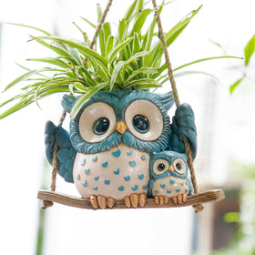 Saysmile Swing Owl Planter hanging indoors with a playful owl duo and blooming greenery.