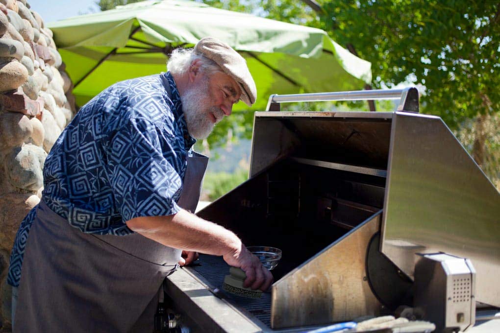 Easy-grip SCRUBIT tool in action on grill grates.