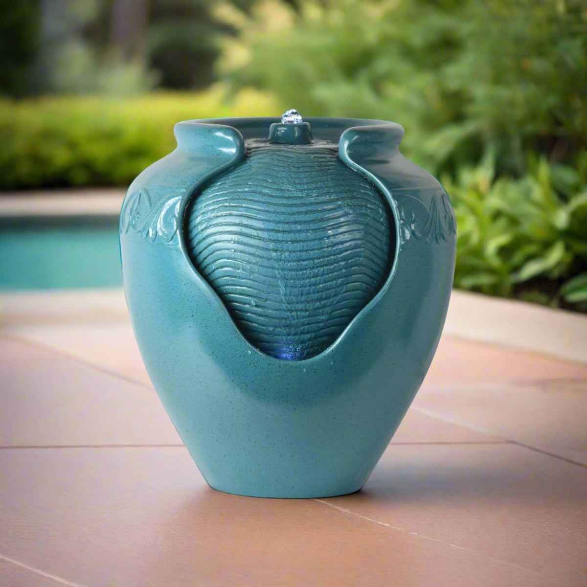 Teamson Home teal fountain lit at night with warm ambient glow.