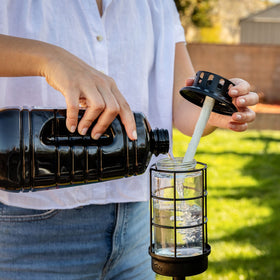 TIKI BiteFighter fuel being poured into a torch canister for outdoor use.