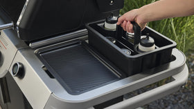 Weber Works Caddy in use beside grill keeps sauces accessible during cooking.