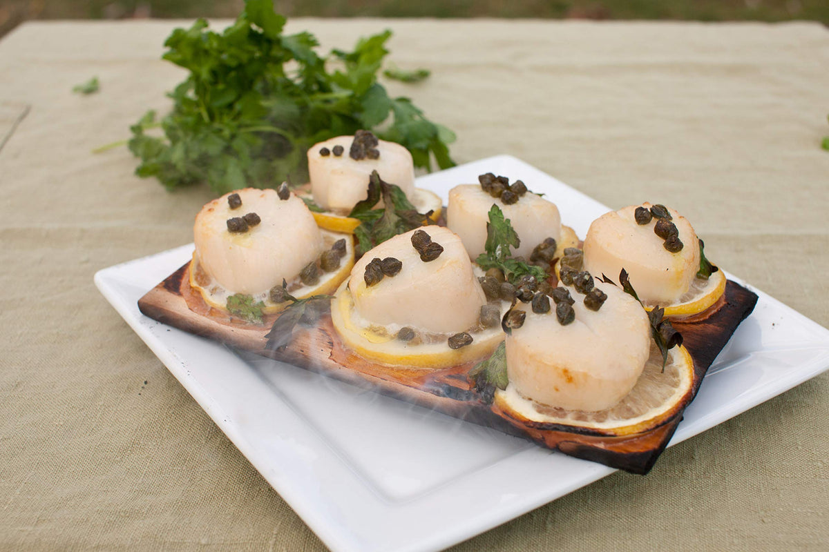 Wildwood Grilling chicken on cedar plank for even cooking.