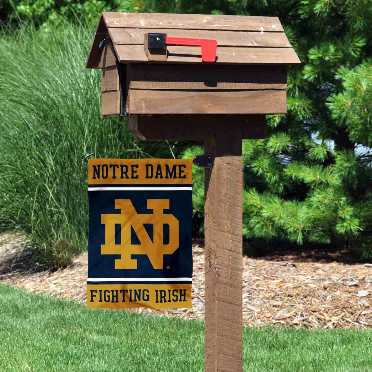 WinCraft Irish ND logo banner flag hanging on a garden stand for outdoor display.