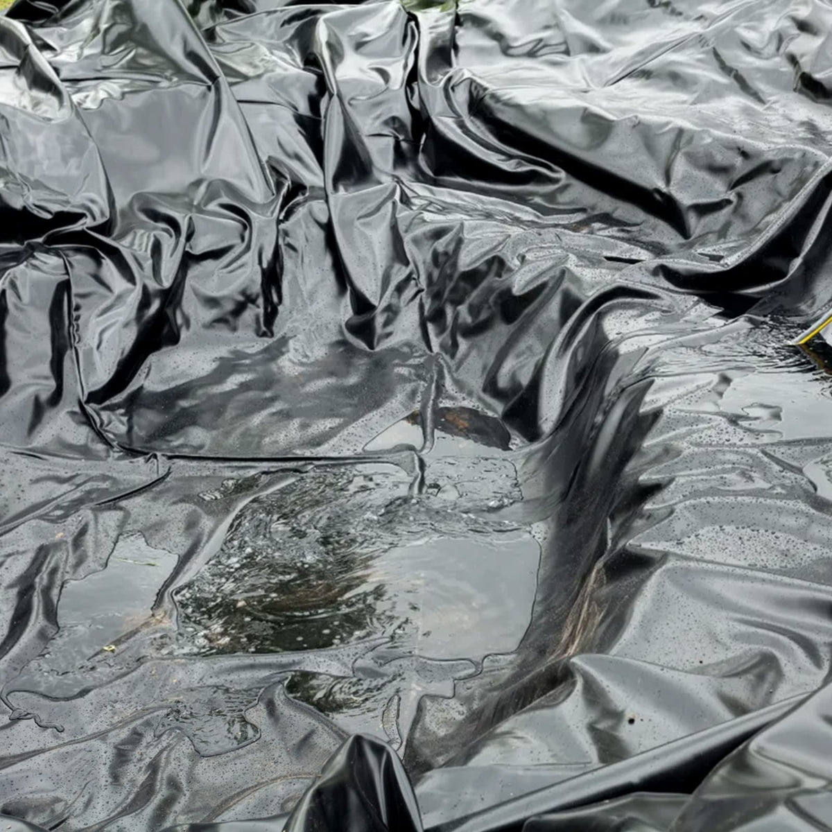 Yarlung black pond liner creates a flat water garden base for features.